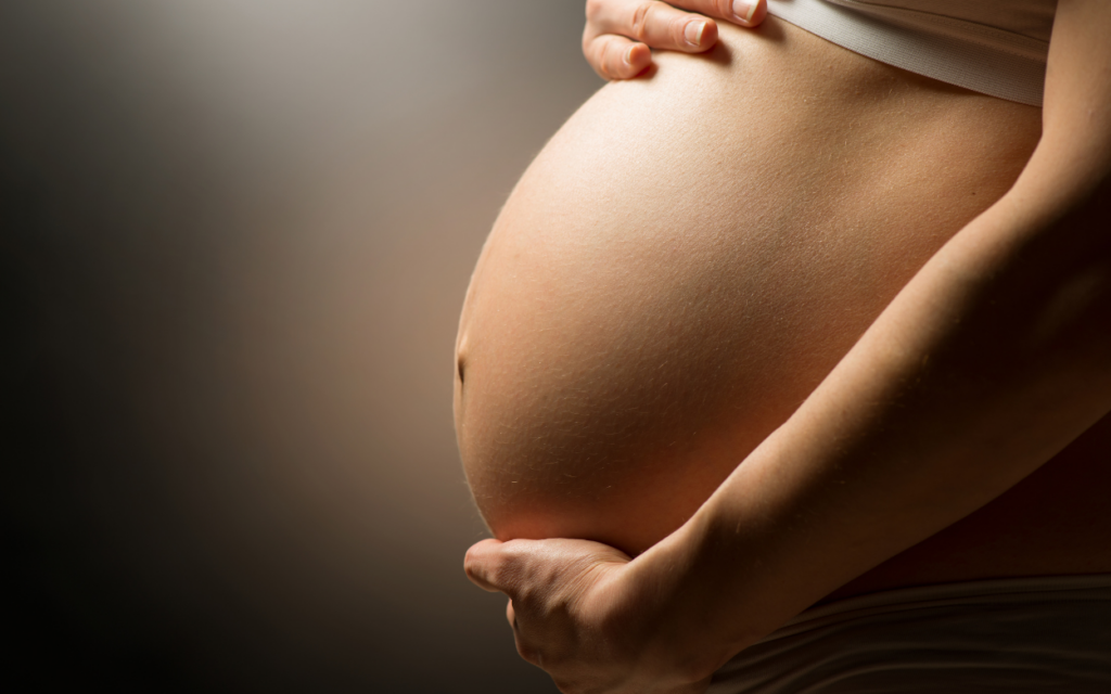 A pregnant woman holding her belly with care.