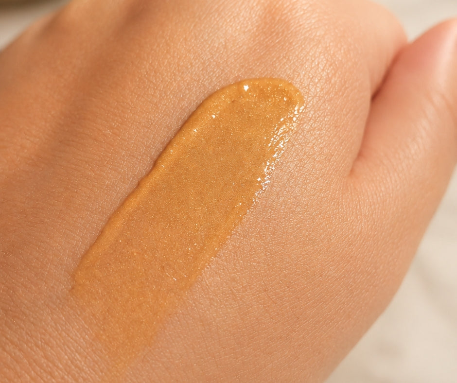 Close-up of Limited Edition Orange Vanilla Wild Sea Kelp Body Lotion on a hand, showing its creamy texture and soft luminous shimmer.